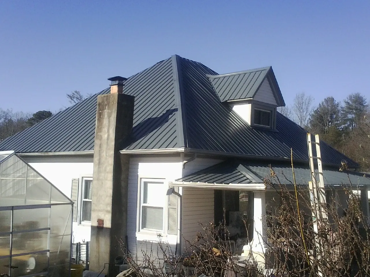 Dark blue standing seam metal roof on a white farmhouse with dormer — Slate & Tile Roof Repair by Roofing Brothers in Jonesborough