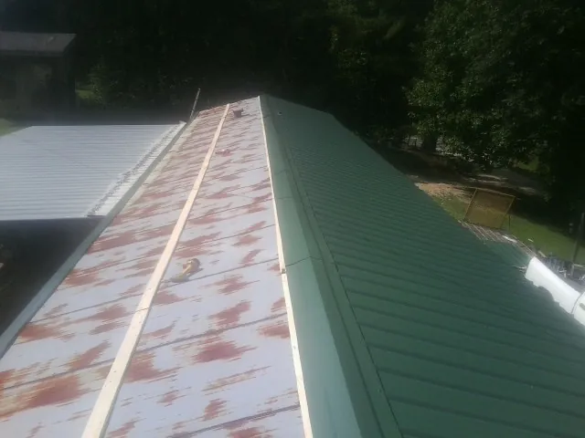 Old rusted panels beside newly installed green metal roofing — Wind Damage Roof Repair by Roofing Brothers in Jonesborough
