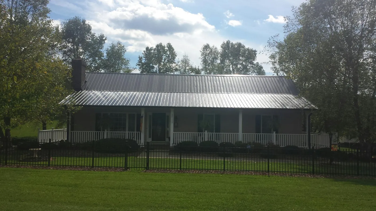Gray metal roof on a brick ranch with a full width front porch — Gutter Guard Installation work by our crew in Jonesborough