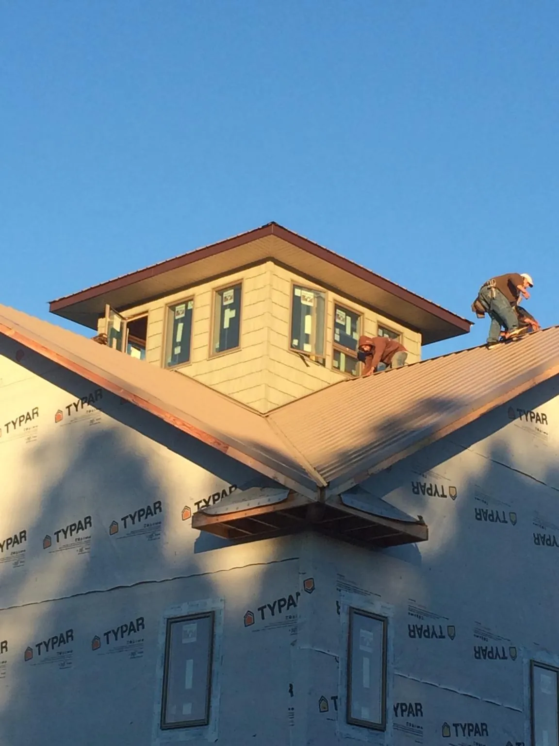 Roofers working around a rooftop cupola on a new metal roof at sunset — Roof Waterproofing in Jonesborough by Roofing Brothers
